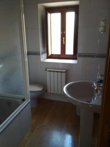 baño con lavabo y aseo y ventana en Casa Valentina, en Villar de Otero