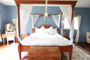 1 dormitorio con cama con dosel y almohadas blancas en Eling Forest Winery, en Sutton Forest