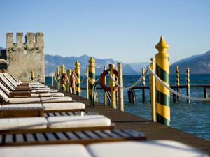 a row of chairs sitting on a dock in the water at Grand Hotel Terme Sirmione in Sirmione