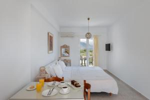 a white bedroom with a bed and a table with food on it at Pernari Apartments in Spartià
