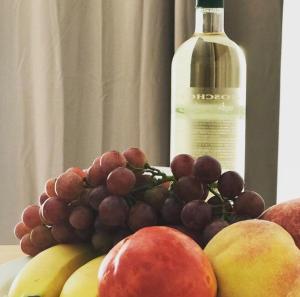 um prato de fruta com uma garrafa de vinho em Royal Sunset Studios & Apartments em Limassol