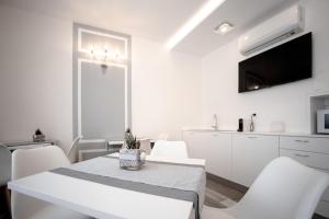 a white dining room with a table and white chairs at Residenza Ca’ Vittoria in Chioggia