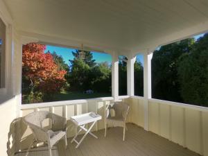 - une terrasse couverte avec 2 chaises, une table et 2 fenêtres dans l'établissement Gunyah Country Estate, à Windwhistle