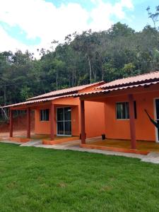 pomarańczowy dom z zielonym trawnikiem przed nim w obiekcie Praia do Jatobá w mieście São Jorge