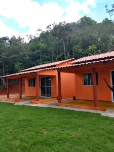 an orange house with a green lawn in front of it at Praia do Jatobá in Sao Jorge