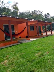 une maison orange avec une pelouse verte devant elle dans l'établissement Praia do Jatobá, à Sao Jorge