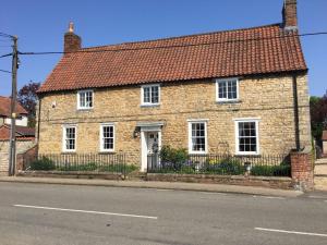 a brick house with a red roof on a street at Clarke’s Farm in Heighington