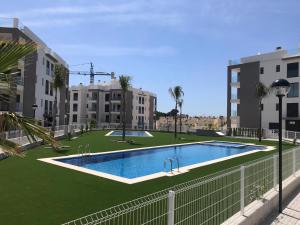 una piscina nel mezzo di un prato con edifici di Bel appartement à moins d 1km du Golf Villamartin a Orihuela