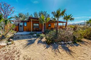 ein kleines Haus mit Palmen davor in der Unterkunft Joshua Tree Bugalow - Downtown in Joshua Tree