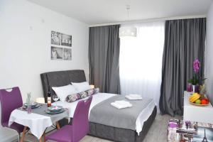 a bedroom with a bed and a table with purple chairs at Small Oasis Apartment in Tivat