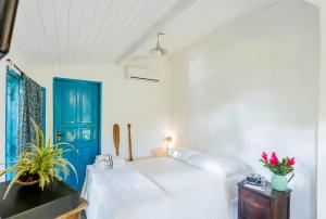 een witte slaapkamer met een bed en een blauwe deur bij Ilhabela Homestay in Ilhabela