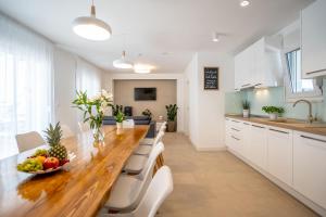 eine Küche mit einem langen Holztisch und weißen Schränken in der Unterkunft Villa Ribalto in Trogir