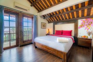 1 dormitorio con 1 cama con almohadas y ventanas de color rojo en Calm House Hotel Hoi An 1, en Hoi An