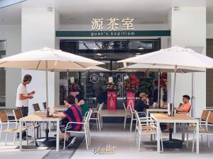a group of people sitting at tables with umbrellas at JY Vacation Home New & Modern Suite Infinity pool-Sutera Avenue in Kota Kinabalu