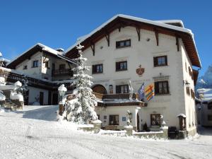 a building in the snow with a christmas tree in front at Schlosshotel Chastè in Tarasp