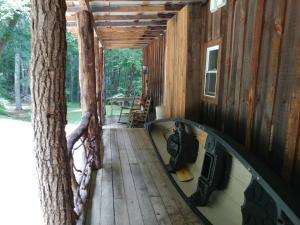 un porche de una cabaña con un árbol y un espejo en Arrowmont Stables & Cabins, en Cullowhee