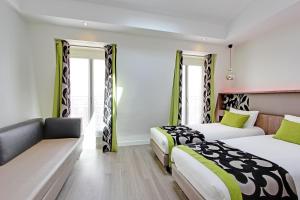 una camera d'albergo con due letti e un divano di Hotel Alhambra a Parigi