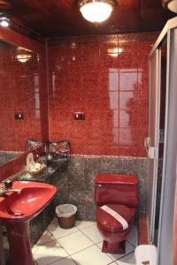 a bathroom with a red toilet and a sink at Hotel Marqueses in Cusco
