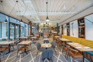 a restaurant with wooden tables and chairs and windows at Sudima Christchurch City in Christchurch