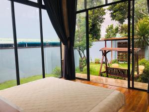 a bedroom with a bed and large glass windows at The Stay Villa Pleiku in Pleiku