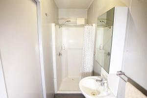 a white bathroom with a shower and a sink at The Greenhoose in Iron Range