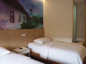 una camera d'albergo con due letti e un dipinto sul muro di The City Hotel a Ambon