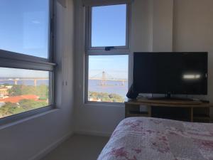 a bedroom with a tv and two windows with a bridge at Departamento 2 ambientes sobre el río Paraná Con Cochera in Corrientes