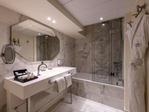 une salle de bain avec une baignoire, un lavabo et une douche dans l'établissement Le Louis Hotel Versailles Château - MGallery Collection, à Versailles