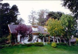 a white house with trees and a yard at Bellevue in San Carlos de Bariloche