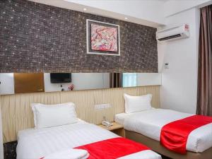 ein Hotelzimmer mit zwei Betten und einem Spiegel in der Unterkunft 906 Premier Hotel in Malakka