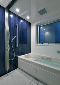 a bathroom with a tub and a shower with a window at Randor Hotel Sapporo Suites in Sapporo