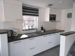 a white kitchen with a sink and a window at Veers Vertier in Veere