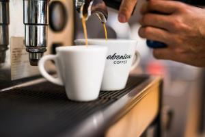 a person pouring coffee into two cups on a counter at Hotel Kochau in Kováčová