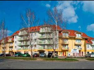 um grande edifício com carros estacionados em frente em Happy apartment em Zalakaros