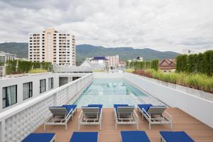 清迈Novotel Chiangmai Nimman Journeyhub的一个带椅子的阳台和一个位于大楼内的游泳池