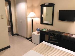 a hotel room with a desk and a mirror at Tower Inn Makati Business Hotel in Manila