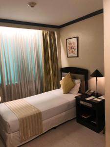 a hotel room with a bed and a window at Tower Inn Makati Business Hotel in Manila