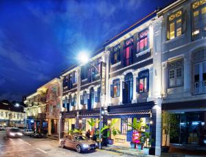 ein Gebäude mit einem Auto, das nachts auf einer Straße parkt in der Unterkunft Hotel Soloha at Chinatown in Singapur