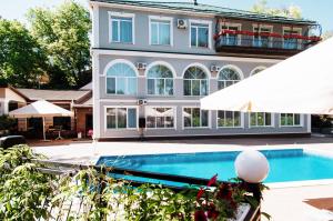 ein Haus mit einem Pool vor einem Gebäude in der Unterkunft Отельно-ресторанный комплекс Златогор in Lubny