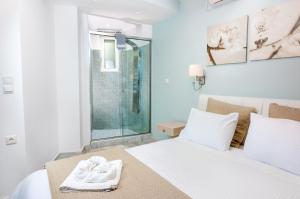a bedroom with a white bed and a glass shower at Christina Beach Hotel in Chania Town