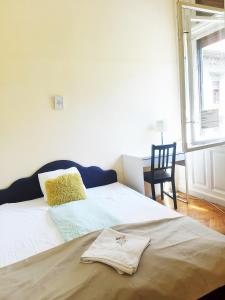 1 dormitorio con 1 cama con silla y ventana en Historic Rooms near Gozsdu Udvar, en Budapest