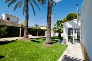 a yard with palm trees and a hammock between two houses at Els Poblets WD by CARLOSFERIEN in Els Poblets