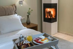 a tray of breakfast food on a bed with a fireplace at Edem Luxury Apartments in Nea Peramos