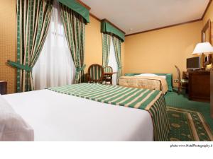 a hotel room with two beds and a table at Grand Hotel Trento in Trento