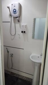 ein weißes Badezimmer mit einem Waschbecken und einem Spiegel in der Unterkunft MELAKA HOMESTAY in Malakka