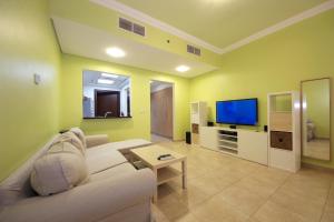 a living room with a couch and a flat screen tv at SHH- Studio Apartment Venetian Tower, Sports City in Dubai