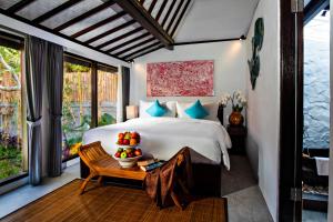 a bedroom with a bed and a table with fruit on it at Canvas Escape Resort in Ubud