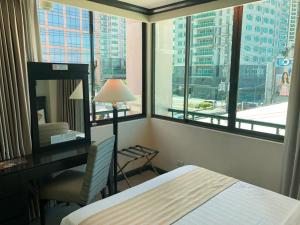 a hotel room with a bed and a desk and window at Tower Inn Makati Business Hotel in Manila