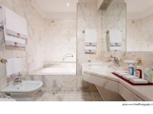 a bathroom with a tub, sink, and mirror at Grand Hotel Trento in Trento