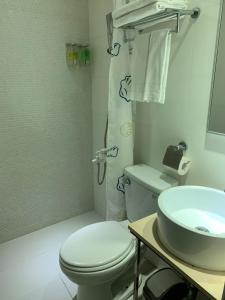 a white bathroom with a toilet and a sink at Herb Art Hotel in Keelung